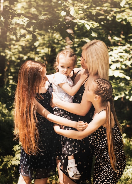 A mother and three daughters cuddle in the summer in nature. Large family. spending time outdoors, happy family life