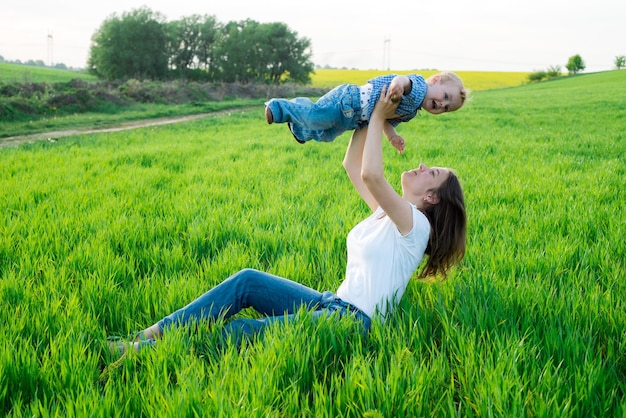 Mother throws baby and play with him on the field