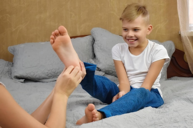 Mother tickling son The parent teases the child Fun games with mom Mother and son on bed