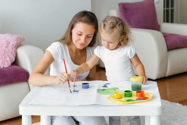 Mother and toddler child painting at home creative family