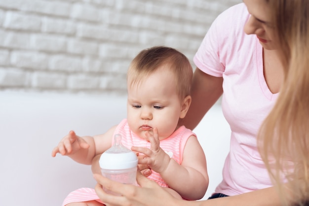 Матери пытаются кормить ребенка бутылочкой молока домой.