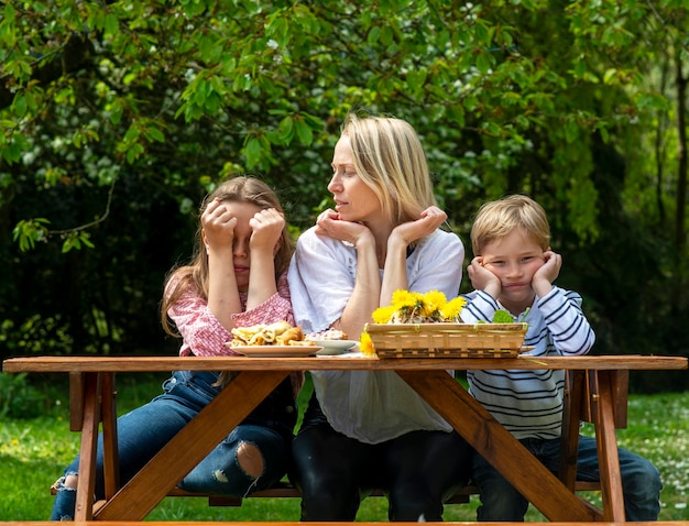 Mother and two children a boy and a girl at the table a family photo a sister is jealous of her mother to her brother