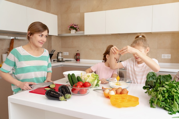 Mother and two daughters cooking in the kitchen and having fun, happy family and single mother concept