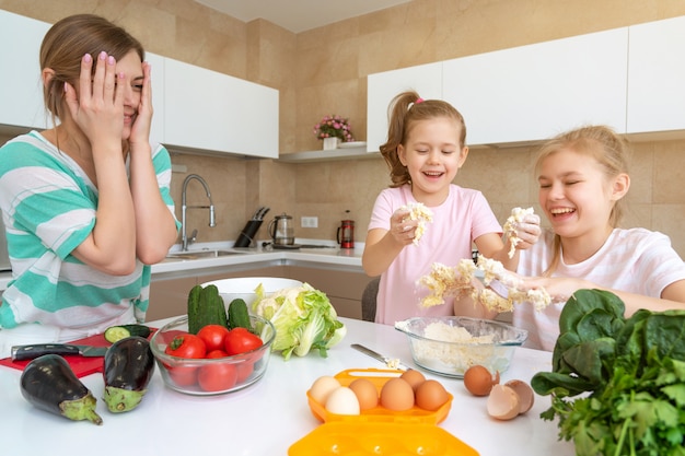 Mother and two daughters cooking in the kitchen and having fun, happy family and single mother concept