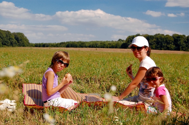 Mother and two kids having picnic outdoors