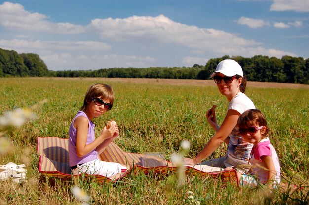Madre e due bambini che hanno picnic all'aperto
