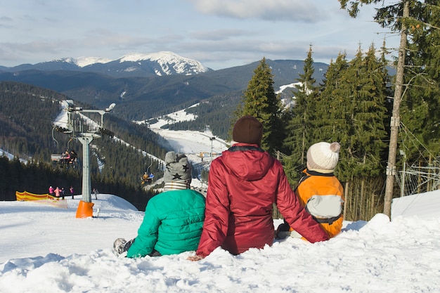 Mother and two sons are sitting on a ski resort