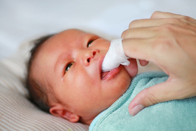 Mother use finger to clean baby tongue and gum 