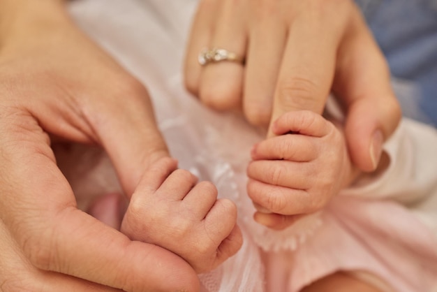 Mother uses her hand to hold her babys tiny hand to make him feeling her love warm and secure