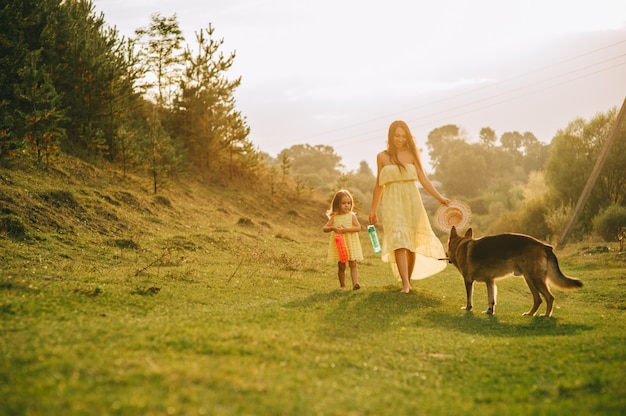 La madre cammina con la sua piccola figlia e il loro cane