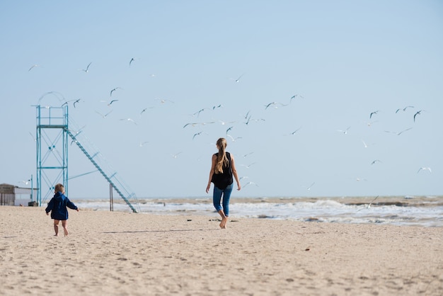 Madre che cammina sulla spiaggia con suo figlio