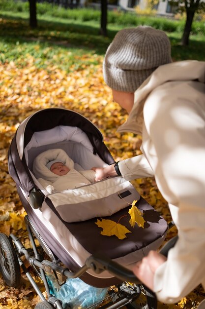 Foto madre che cammina nel parco con un passeggino nel parco