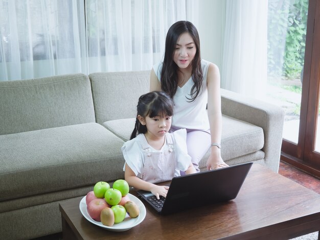 Mother watching daughter playing computer