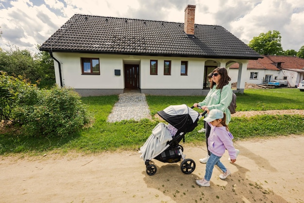 Mother with baby carriage and kids walking in village