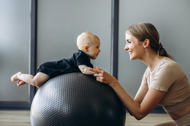 Мать с маленькой дочерью тренируется с мячом для йоги