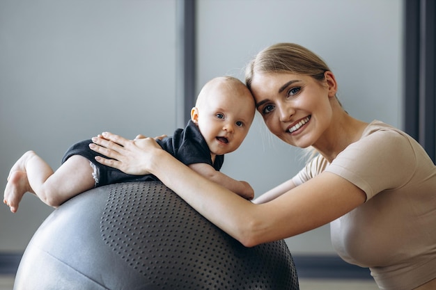 Mother with baby daughter sitting on yoga ball