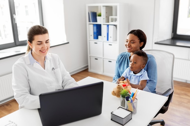 mother with baby and doctor with laptop at clinic