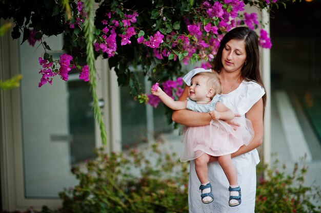 紫色の花に対してトルコのリゾートの女の赤ちゃんを持つ母親。