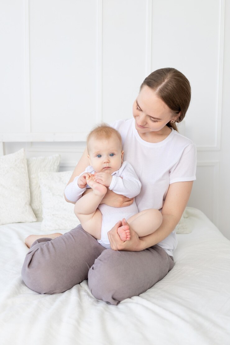 Photo 赤ちゃんを抱いた母親が、自宅のベッドで子供を優しく抱きしめます
