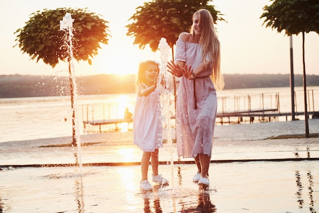 Mother with baby near the fountain at sunset