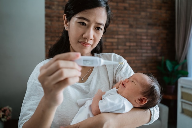 Mother with baby newborn and thermometer