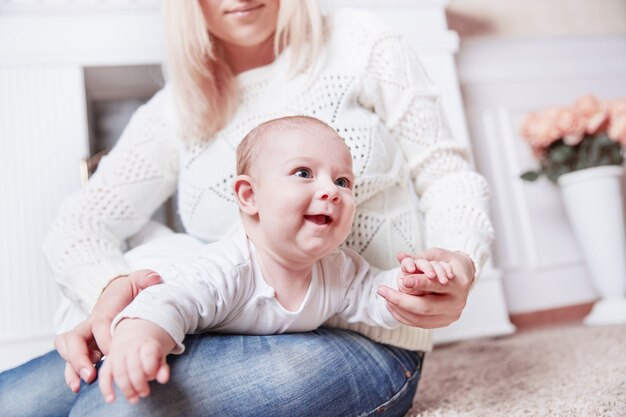 Mother with baby sitting near the fireplace in a cozy living room. photo with copy space