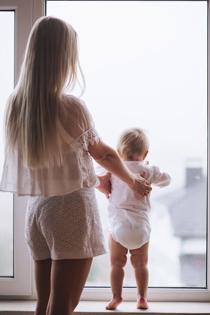 Mother with baby sitting at the window and play