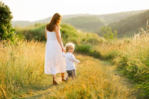 Mother with boy walking holding hands in nature