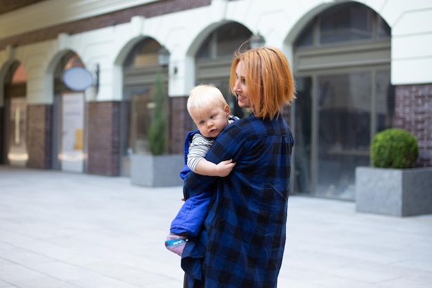 Mother with child baby boy in casual clothes outdoors on urban background