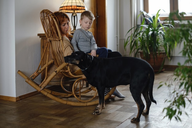 家でロッキングチェアに子供と犬を持つ母