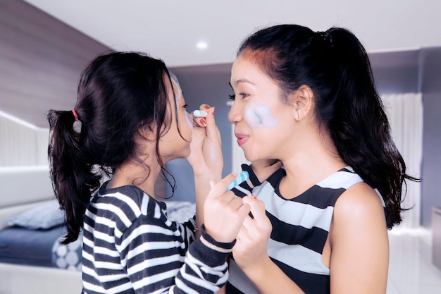 Mother with child doing face painting