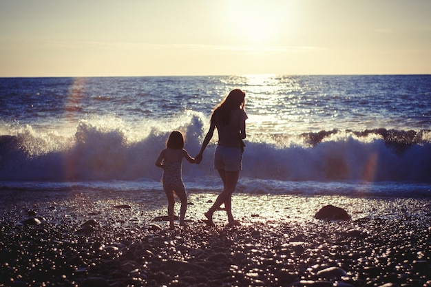 写真 夕暮れの海辺で娘と一緒にいる母親