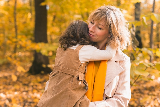 Madre con bambino in braccio sullo sfondo della famiglia della natura autunnale e del concetto di stagione