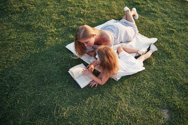 La madre con un bambino legge un libro sull'erba