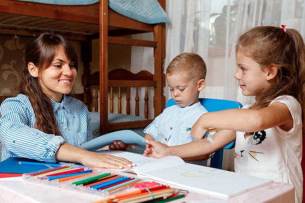 子供を持つ母親がテーブルに座って、子供がホームスクーリングで学ぶ宿題をします