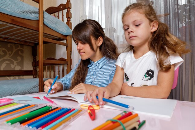 A mother with a child sits at the table and does homework the child learns at home home schooling