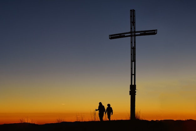 Mother with child on top of the mountain near the cross