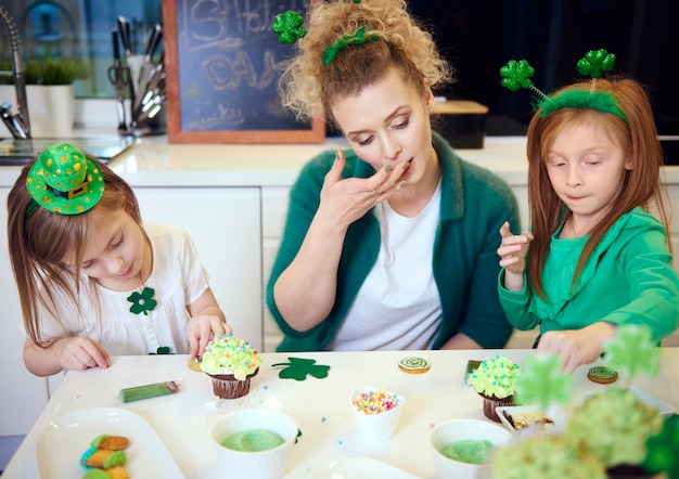 キッチンでカップケーキを飾る子供を持つ母