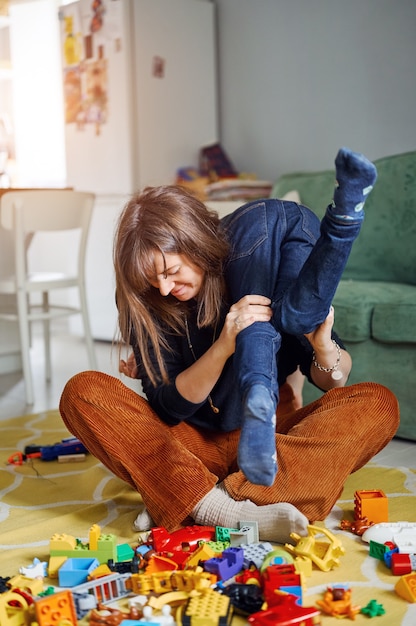 抱きしめ、楽しんで、家で笑っている子供を持つ母親。一緒に時間を過ごす息子を持つ親