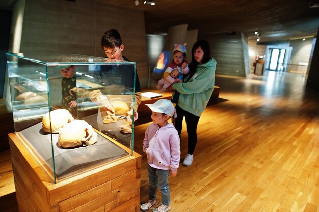 Photo mother with children exploring skulls humans evolution at museum