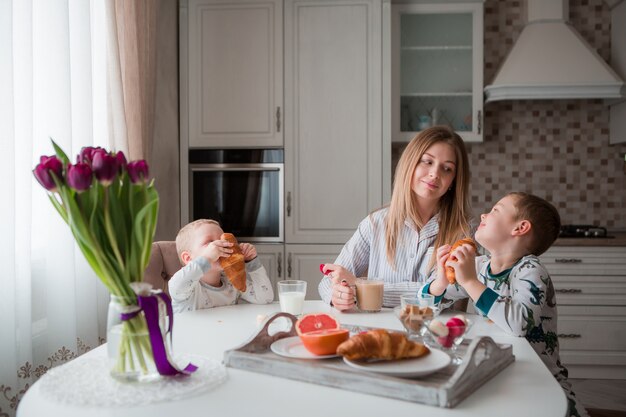 キッチンで朝食を食べている子供を持つ母