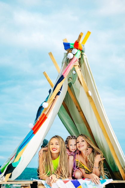 Mother with children playing together in tent. Family camping. Mom with kids Having fun outdoors. Vacation concept. Mothers day, motherhood.