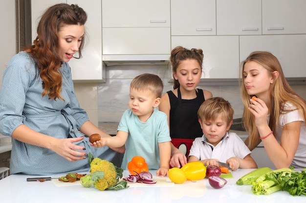 キッチンで野菜を準備する子供を持つ母親