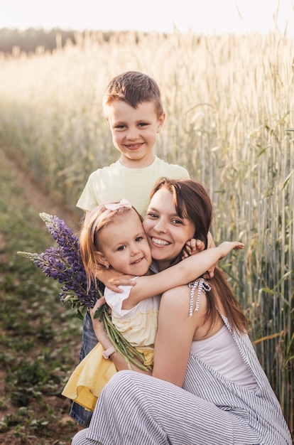 Madre con bambini con figlio e figlia che camminano in un campo di grano