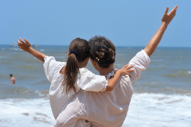 Mother with daughter on beach, back view