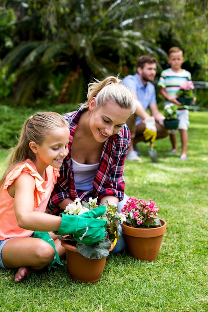 Mother with daughter holding flower pots at yard