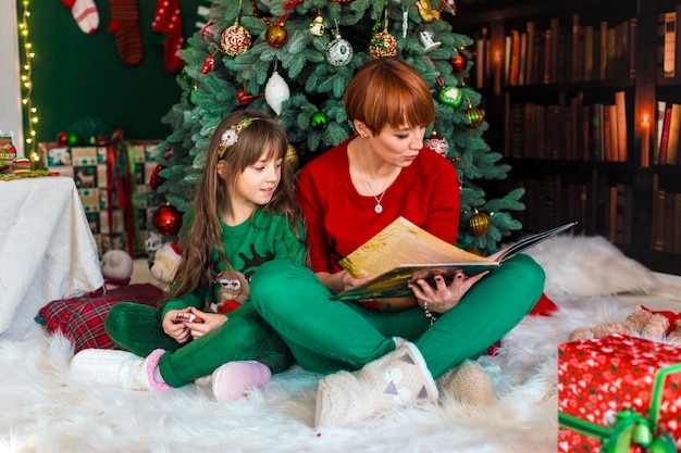 Madre con figlia vicino all'albero di natale