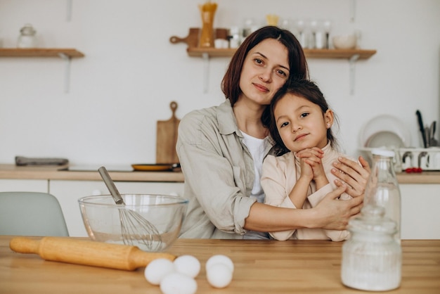 Mother with daughter playing with flour and baking at kitchen