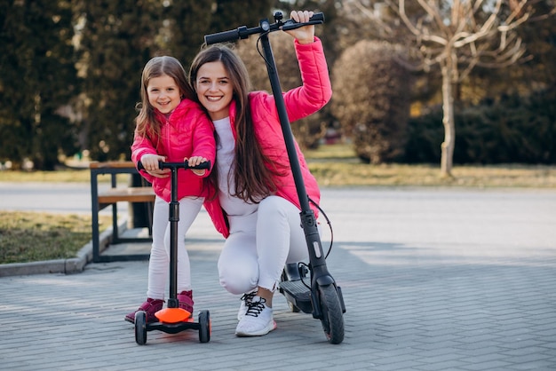 Mother with daughter riding electric scooter