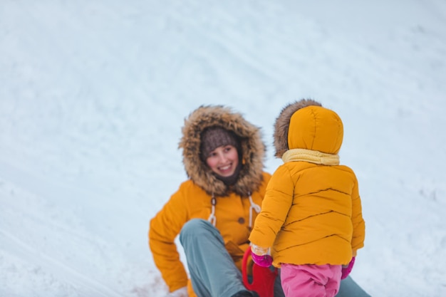 Mother with daughter sliding from winter hill